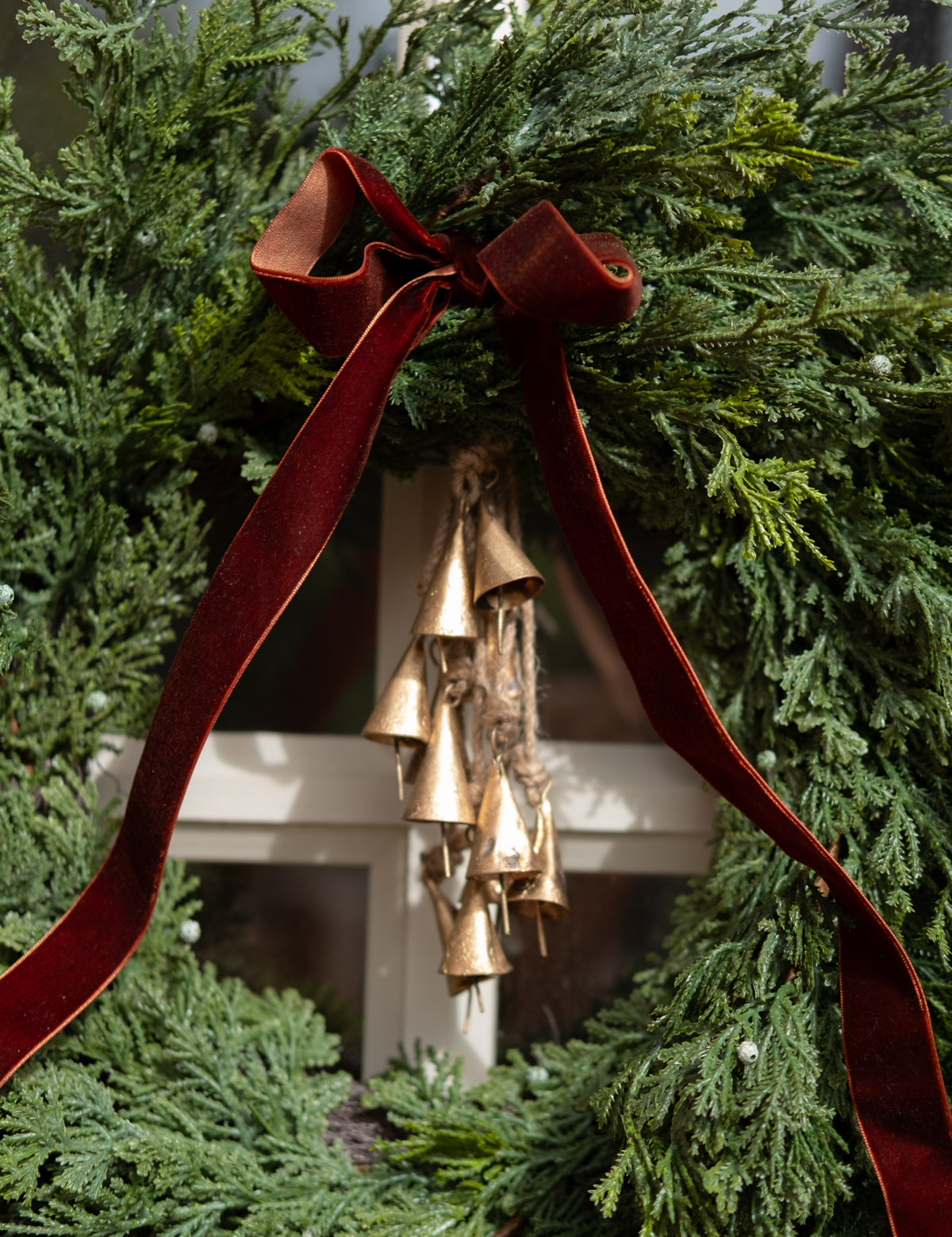 Decorative wreath with gold bells and red ribbon against a green background