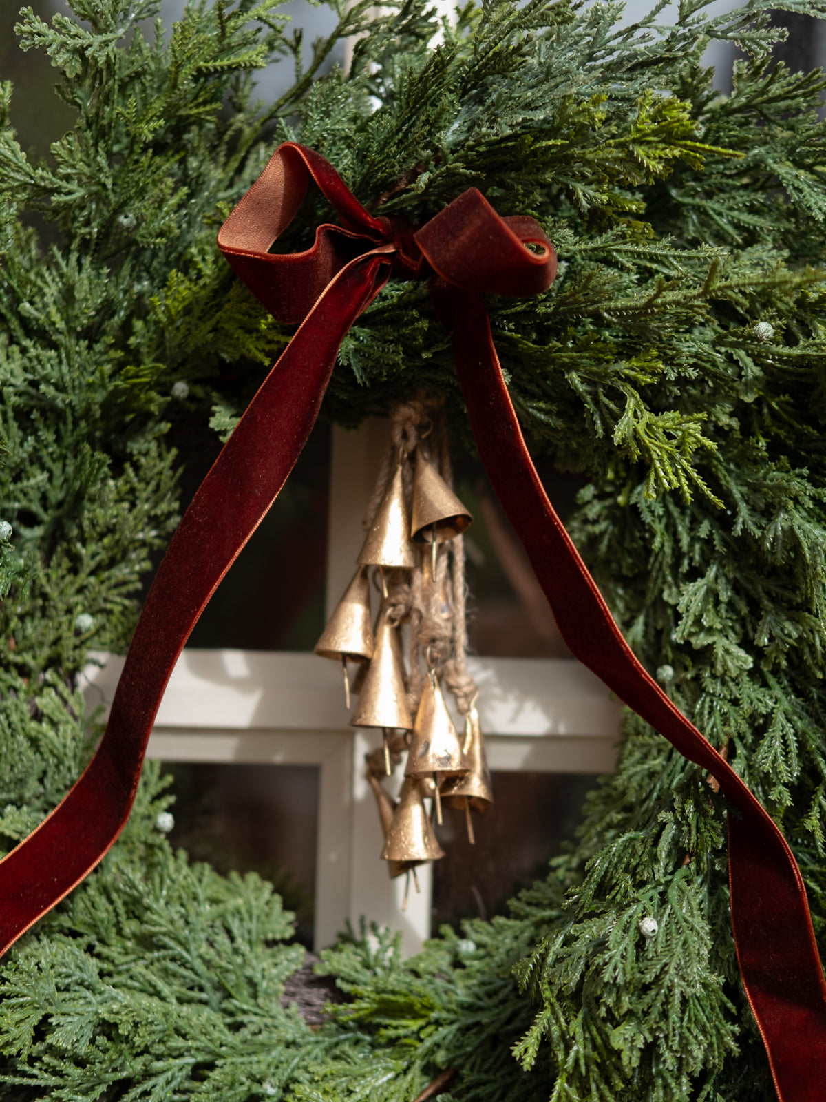 Decorative wreath with gold bells and red ribbon against a green background