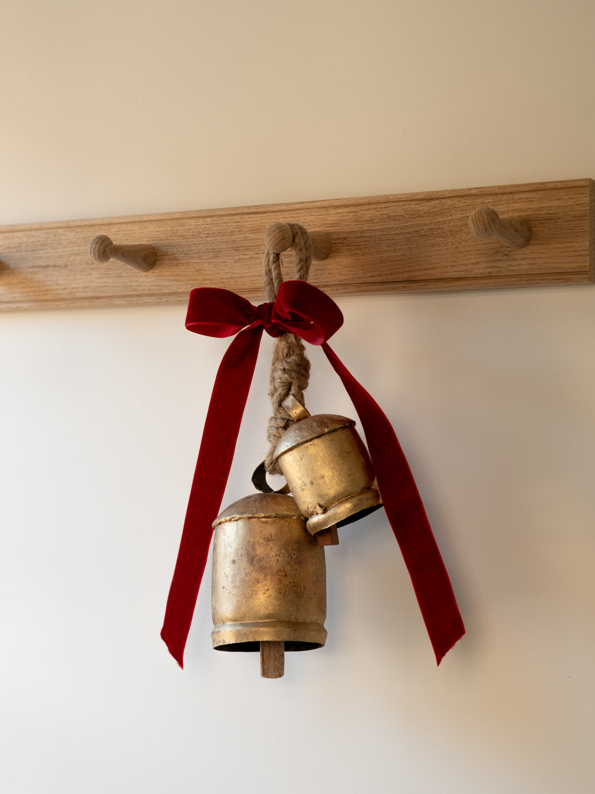 two brass bells hanging with a red ribon tied at the top