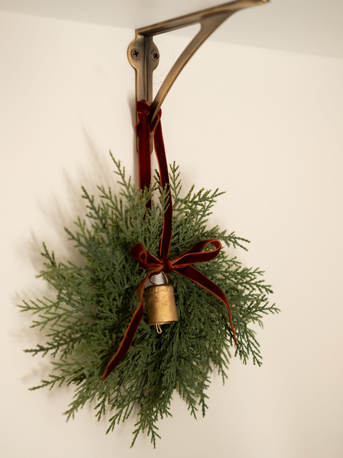 Artificial wreath hanging with a red ribbon with a bell hanging too