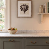 Kitchen interior with gray cabinets, marble countertop, and framed artwork on the wall.