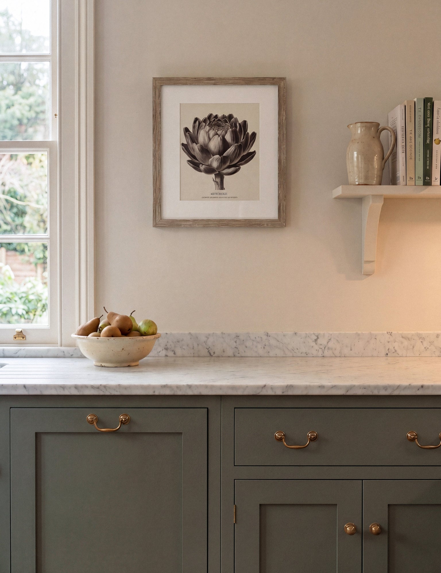 Kitchen interior with green cabinets, marble countertop, and framed artwork on the wall.