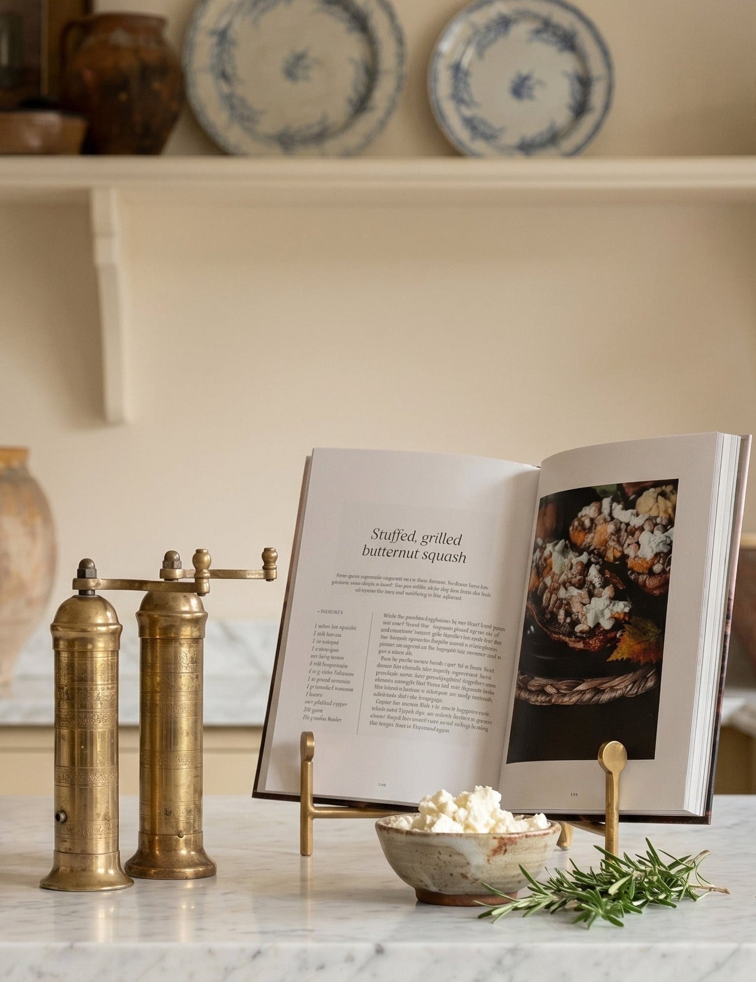 Kitchen counter with marble surface, brass salt and pepper shakers, open cookbook, and decorative items.