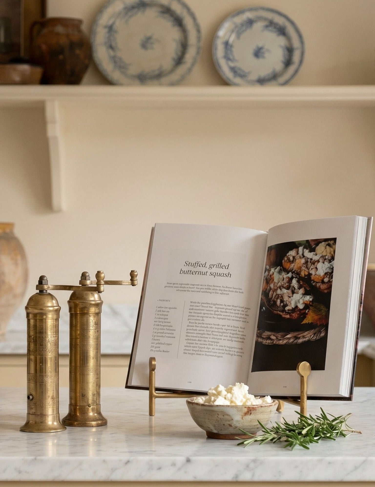 Kitchen counter with marble surface, brass salt and pepper shakers, open cookbook, and decorative items.