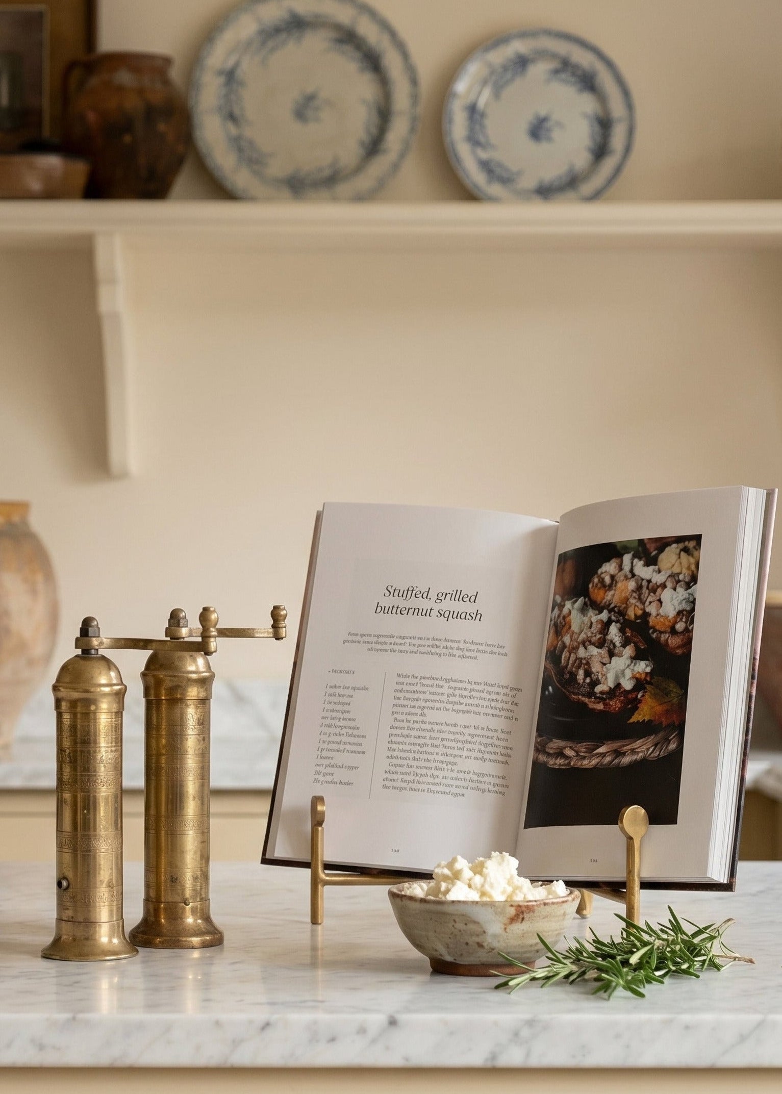 Kitchen counter with marble surface, brass salt and pepper shakers, open cookbook, and decorative items.