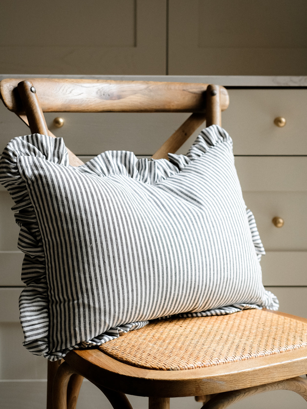 Striped pillow on a wooden chair with a neutral background