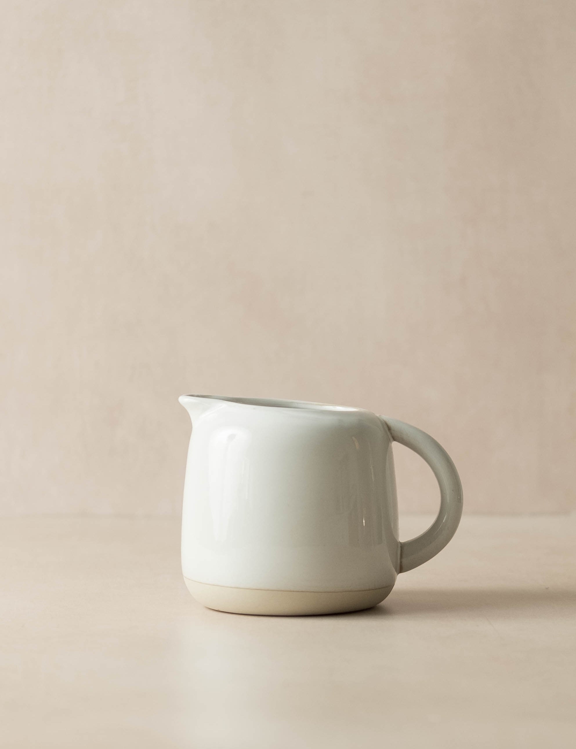 White ceramic pitcher on a beige background