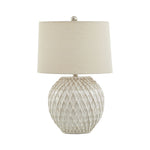Table lamp with textured base and beige shade on a white background
