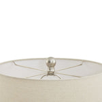 Close-up of a beige lampshade with a metallic finial on a white background