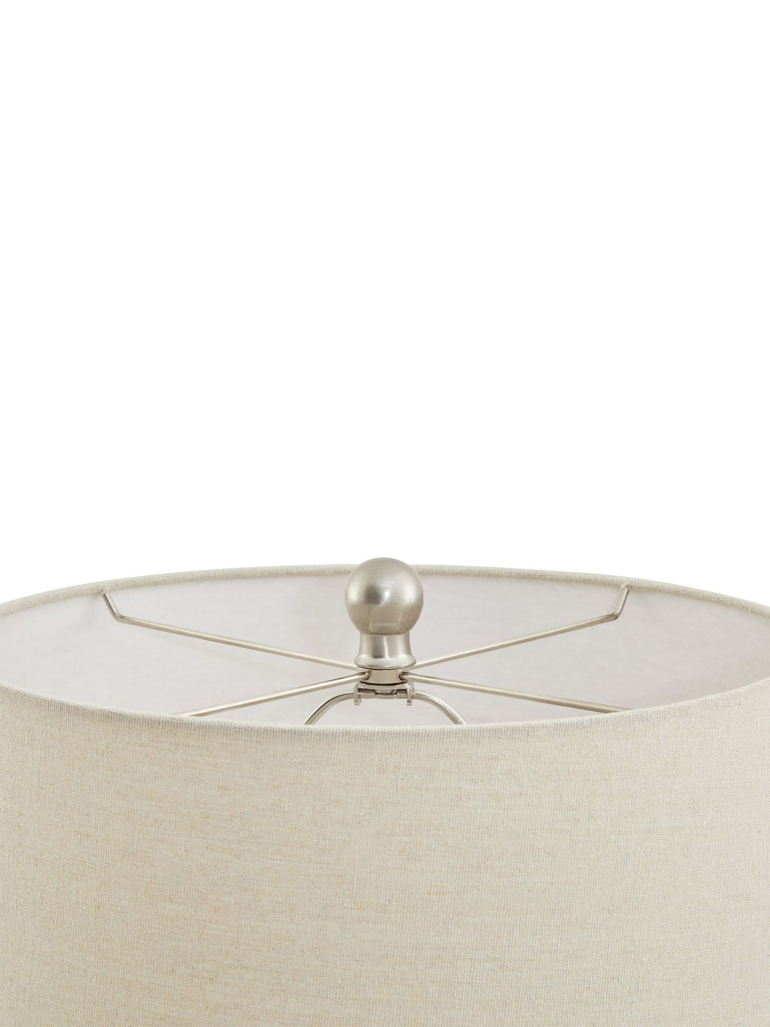 Close-up of a beige lampshade with a metallic finial on a white background