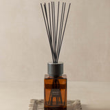 Reed diffuser with black reeds on a beige background