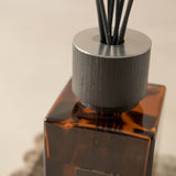 Brown diffuser bottle with black sticks on a neutral background
