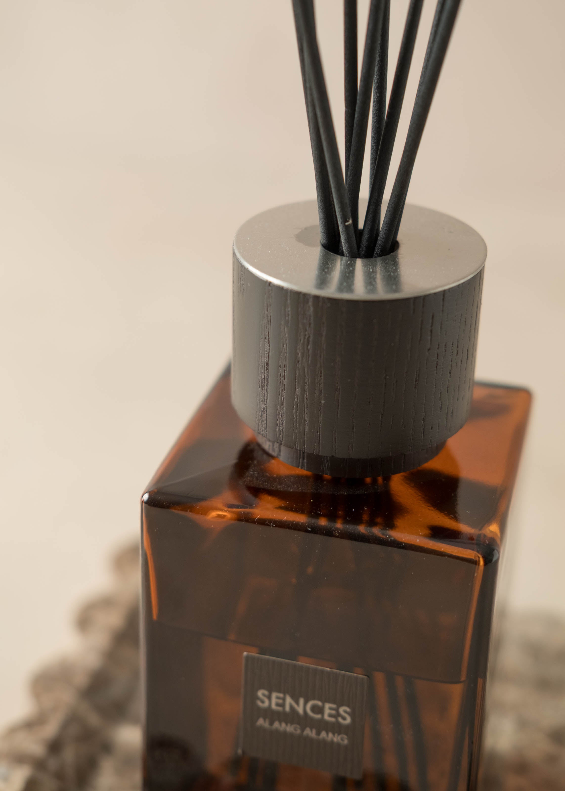 Brown diffuser bottle with black sticks on a neutral background