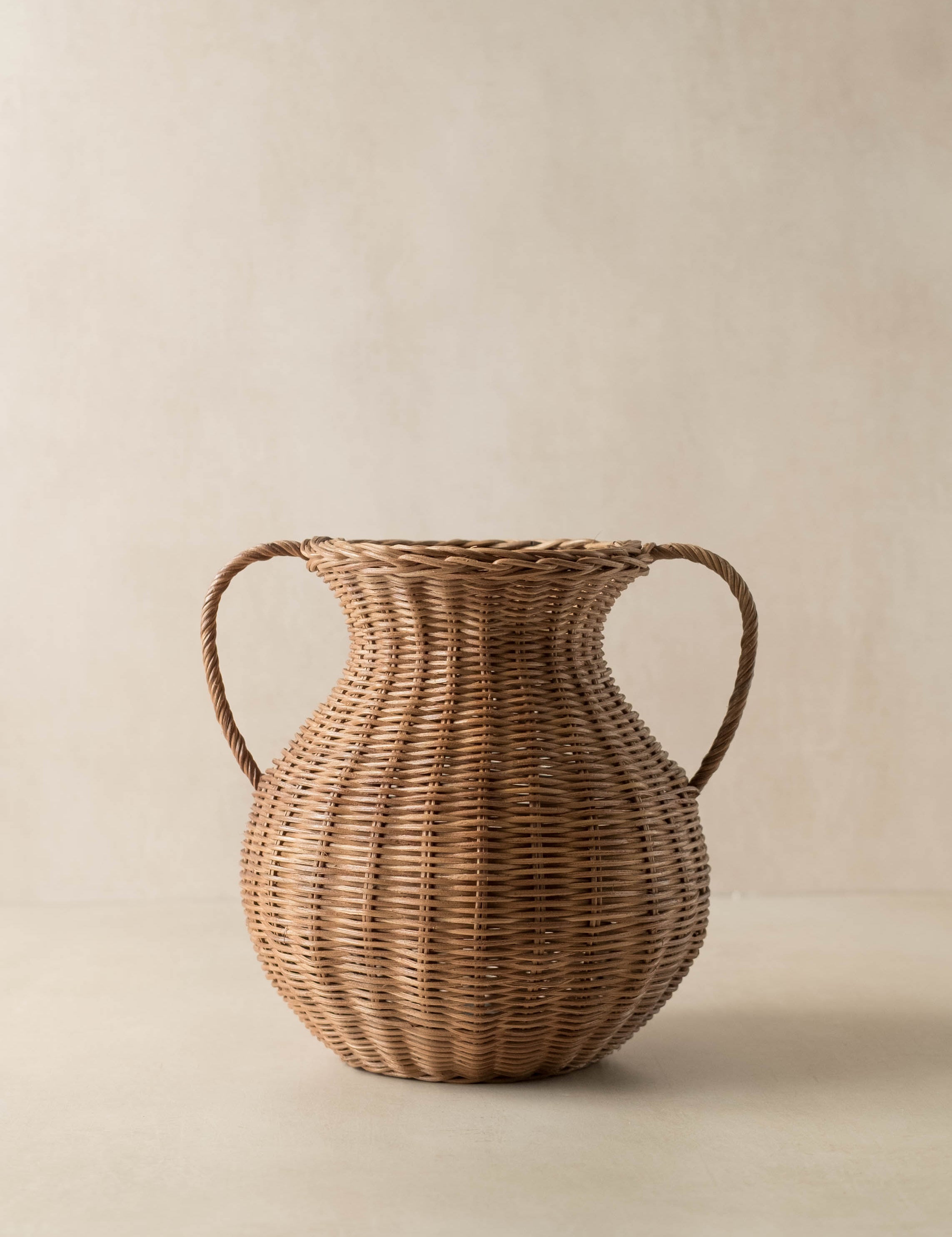 Woven rattan vase with handles on a beige background - McGee and Co style