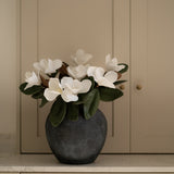Faux flower arrangement in a dark vase on a neutral background