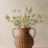 Wicker vase with greenery on a beige background