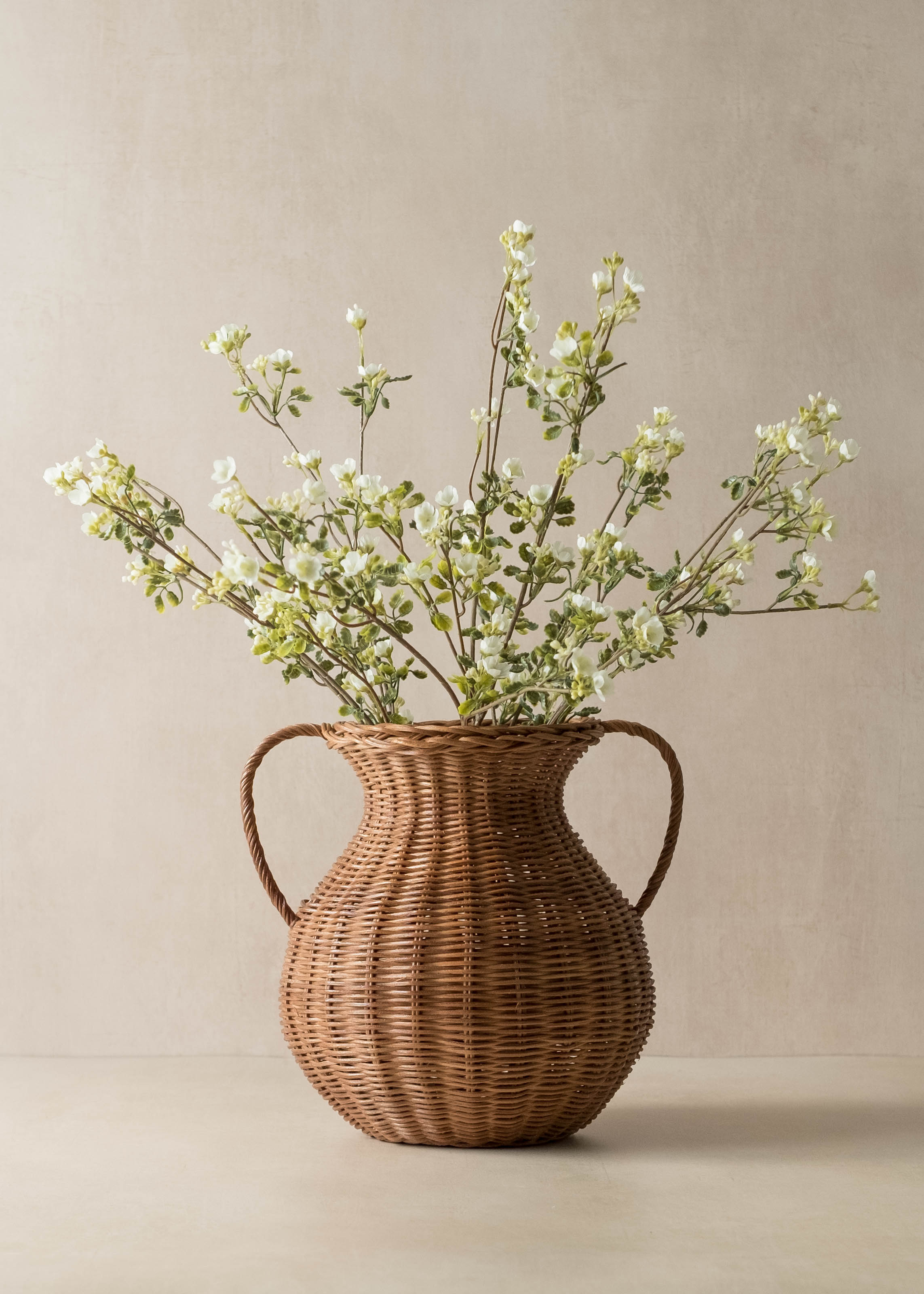 Wicker vase with greenery on a beige background